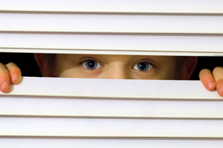 Kid playing hide and seek while peeking through a window